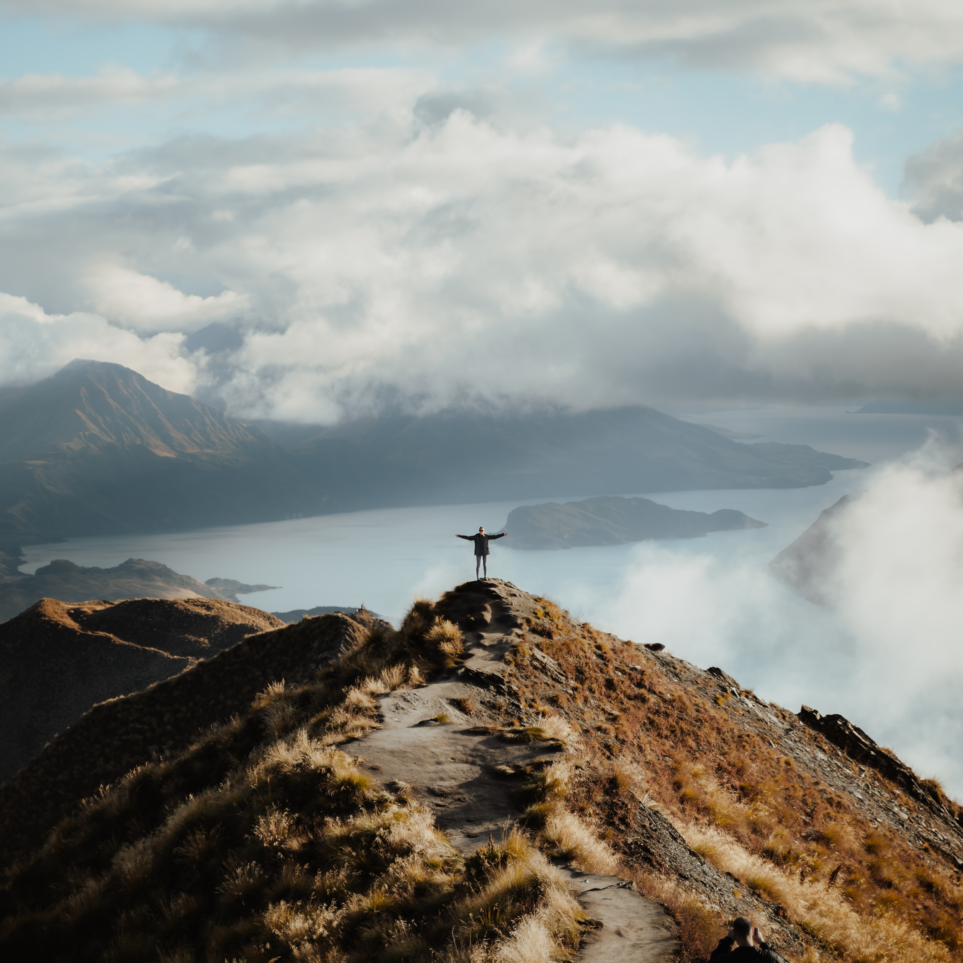 man with hands wide open standing top mountain enjoying incredible view lake 1